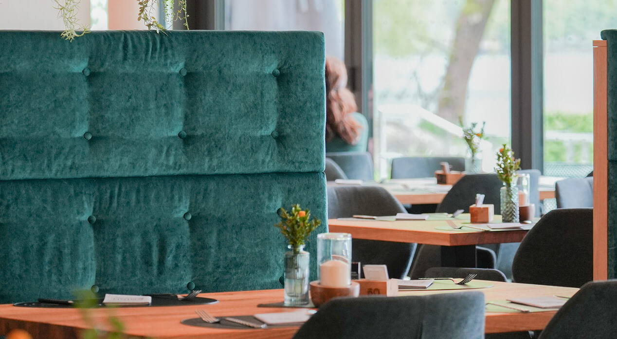 Grüne Polsterbank und Tische in einem Restaurant.
